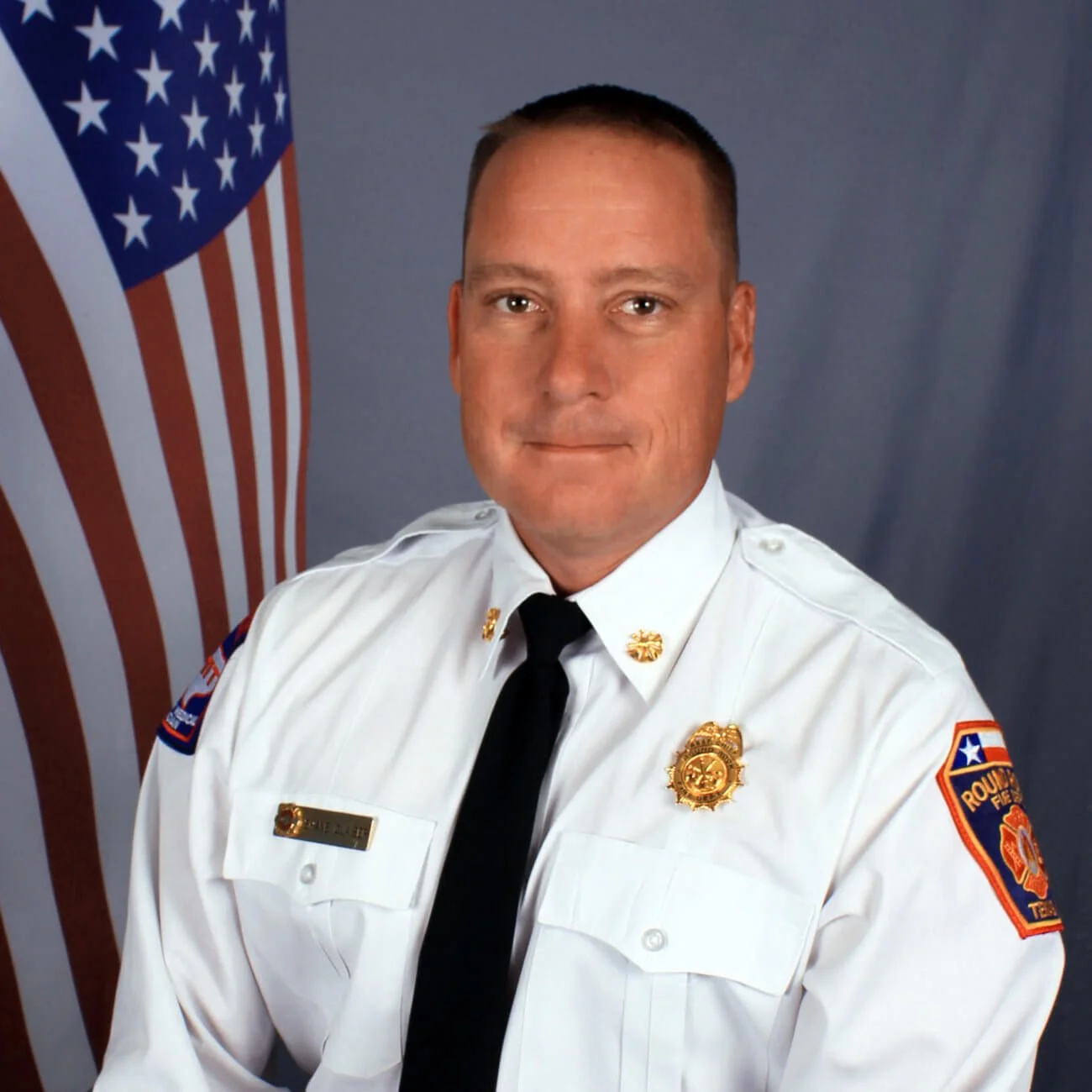Round Rock Fire Chief Shane Glaiser in uniform in front of an American flag
